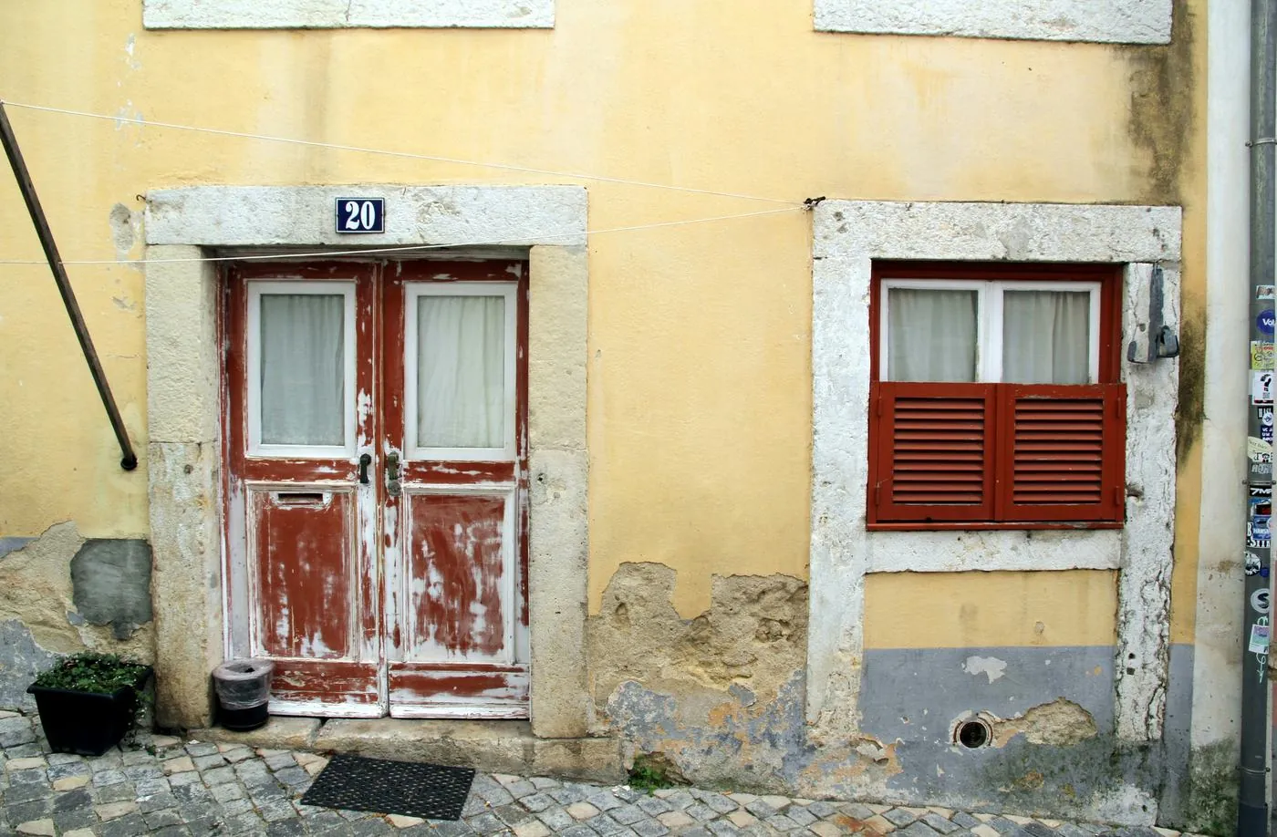Porta e janela de uma casa antiga em Lisboa, com a tinta a descascar e as portadas fechadas